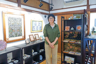 ギャラリーに立つ樋口まなみさん。様々な絵付けタイル作品が並ぶ